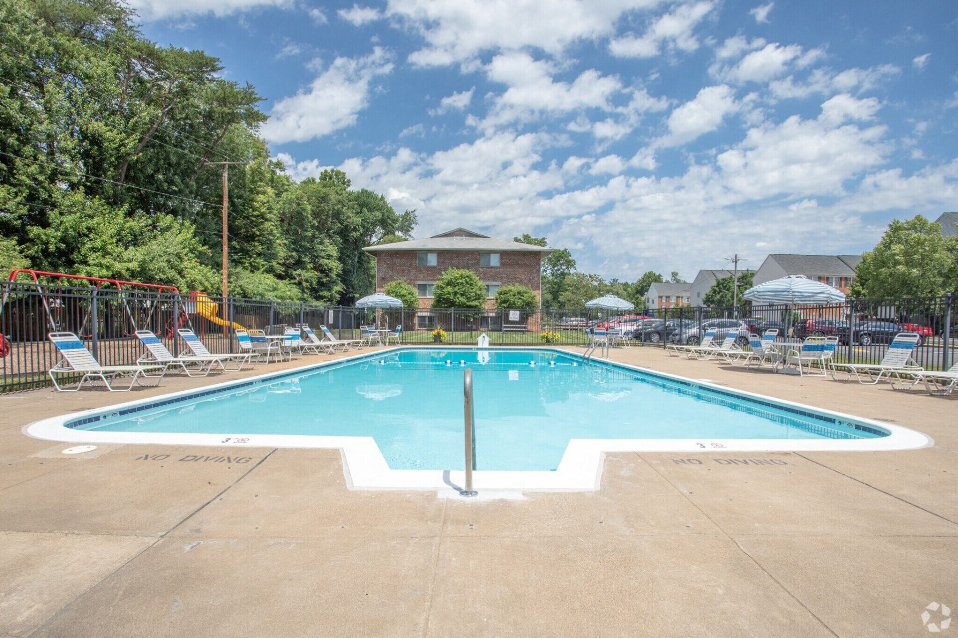 Skyview community swimming pool with lounge chairs and striped umbrellas on a sunny day